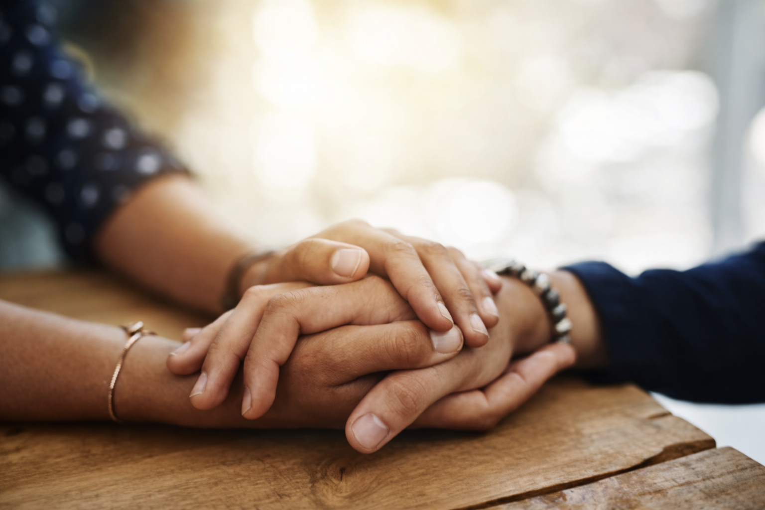 Mãos sendo seguradas em gesto de apoio — quando as palavras não bastam, o consolo de Deus se faz presente