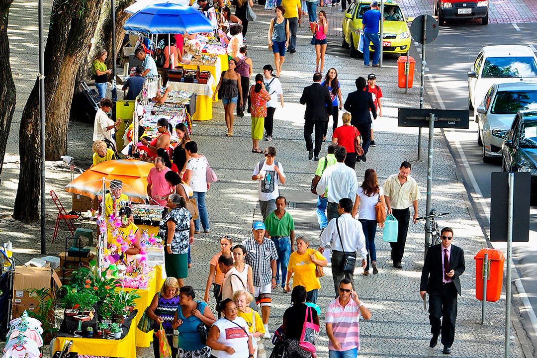 Pessoas caminhando em uma cidade movimentada, lembrando que não temos aqui cidade permanente.